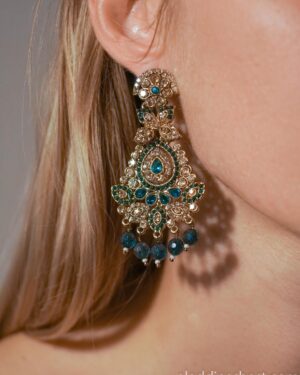 Person wearing ornate blue gold drop earring