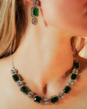 Elegant emerald necklace and earrings on woman's neck.