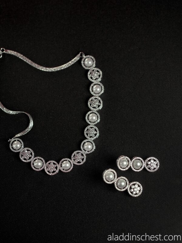 Elegant pearl necklace and earrings on black background