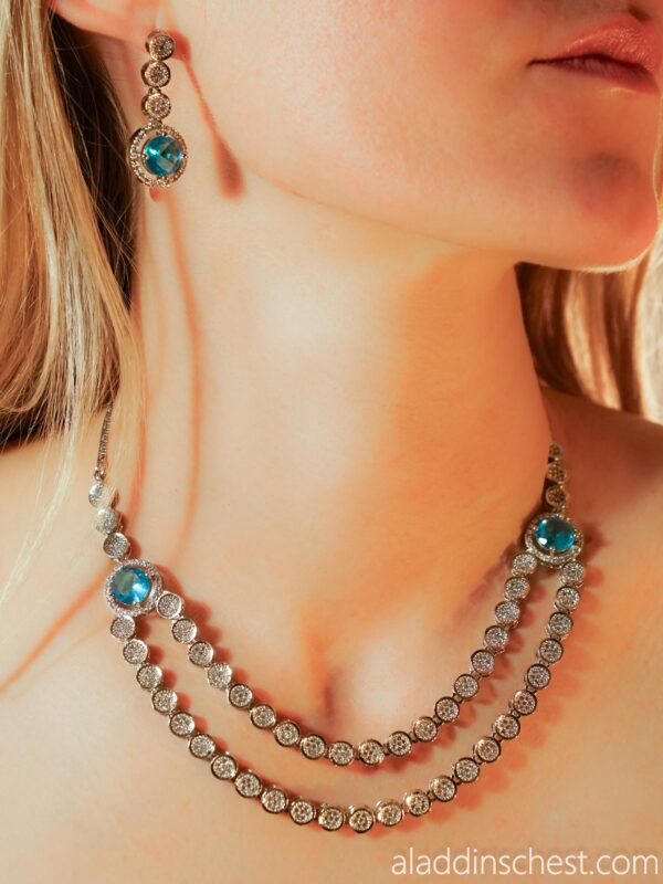 Woman wearing blue gemstone necklace and earrings.