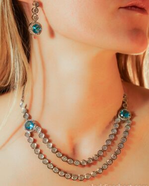Woman wearing blue gemstone necklace and earrings.