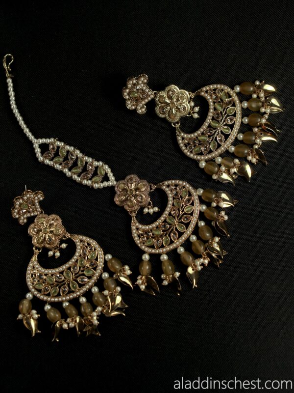 Elegant gold and pearl jewelry on black background.