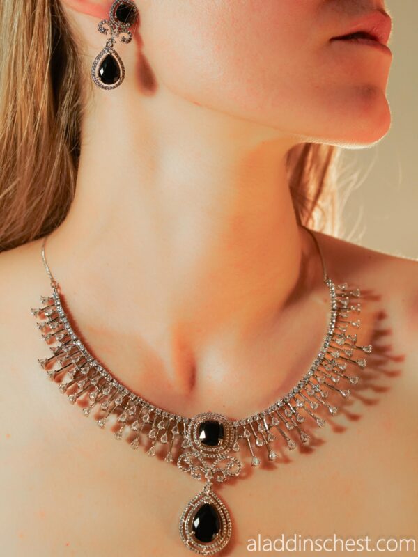 Woman wearing elegant black gemstone necklace and earrings.