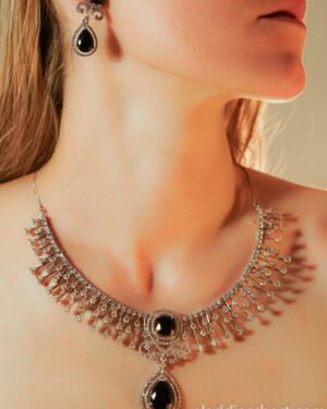 Woman wearing elegant black gemstone necklace and earrings.