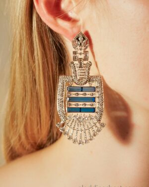 Close-up of ornate silver earring with jewels.