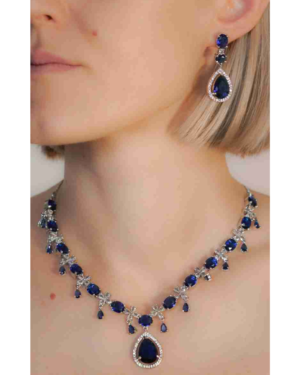 Woman wearing sapphire necklace and earring set.
