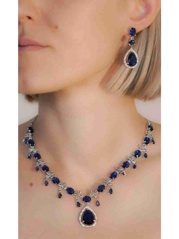 Woman wearing sapphire necklace and earring set.