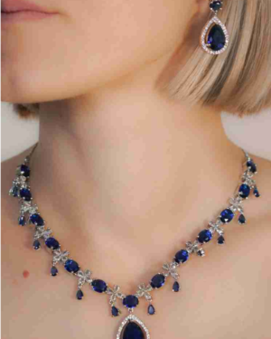 Woman wearing sapphire necklace and earring set.