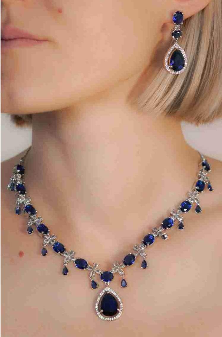 Woman wearing sapphire necklace and earring set.