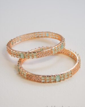 Two elegant gold bangles with green stones.