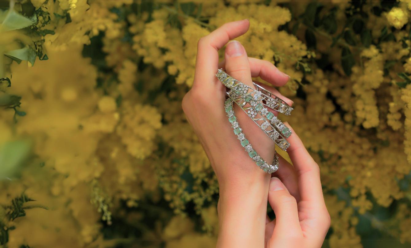Hands holding diamond-studded bracelets in flowers