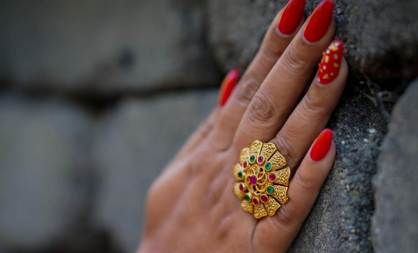 Hand with red nails wearing gold ring