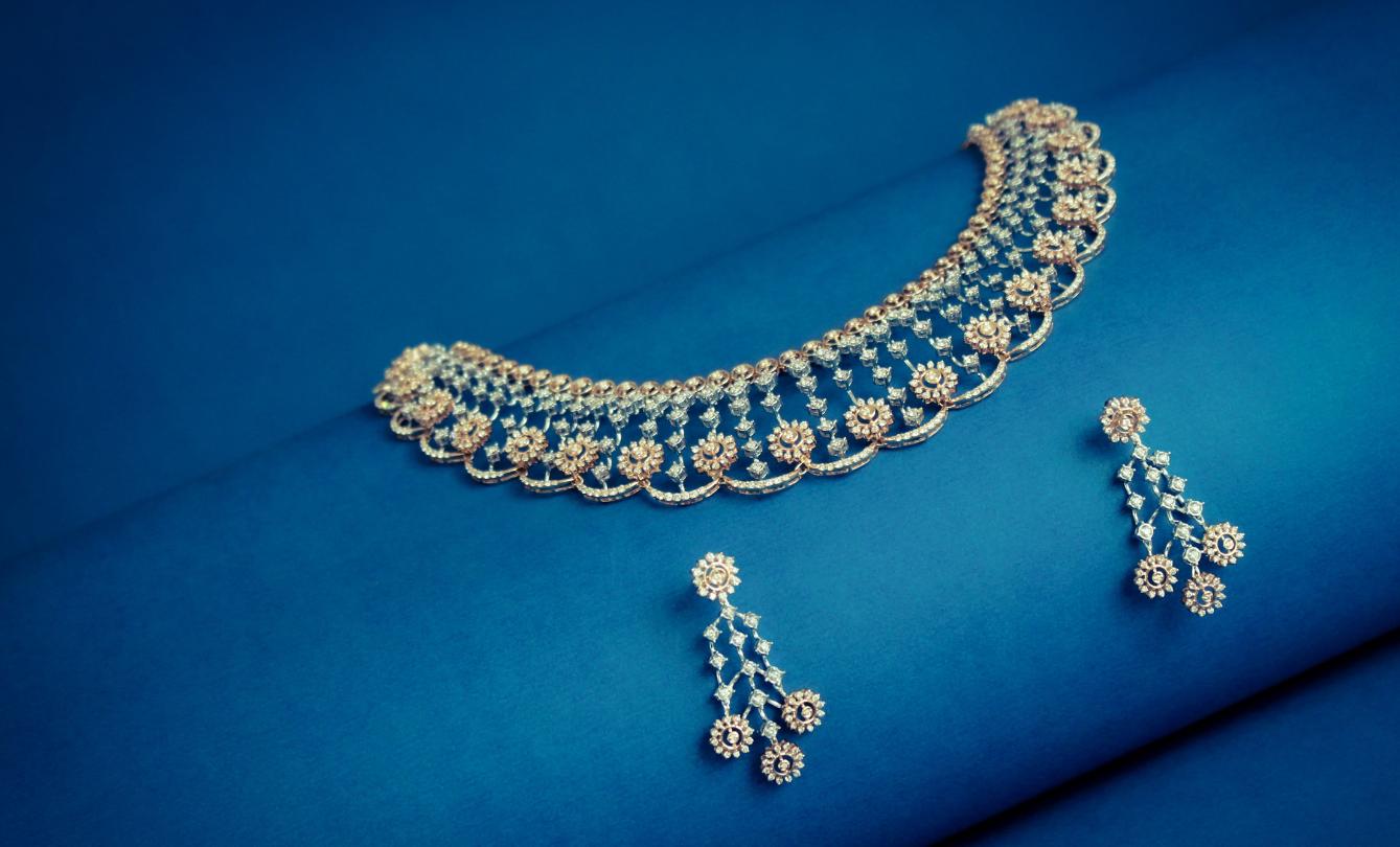 Elegant gold necklace and earrings on blue background.
