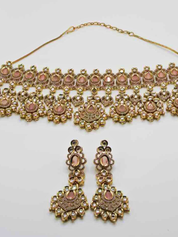 Gold choker necklace and earrings with gemstones.